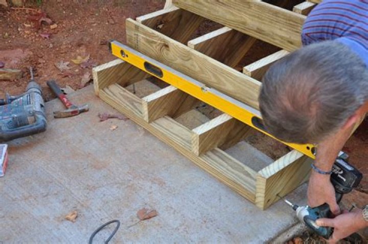 How do I anchor my deck stairs to the ground?